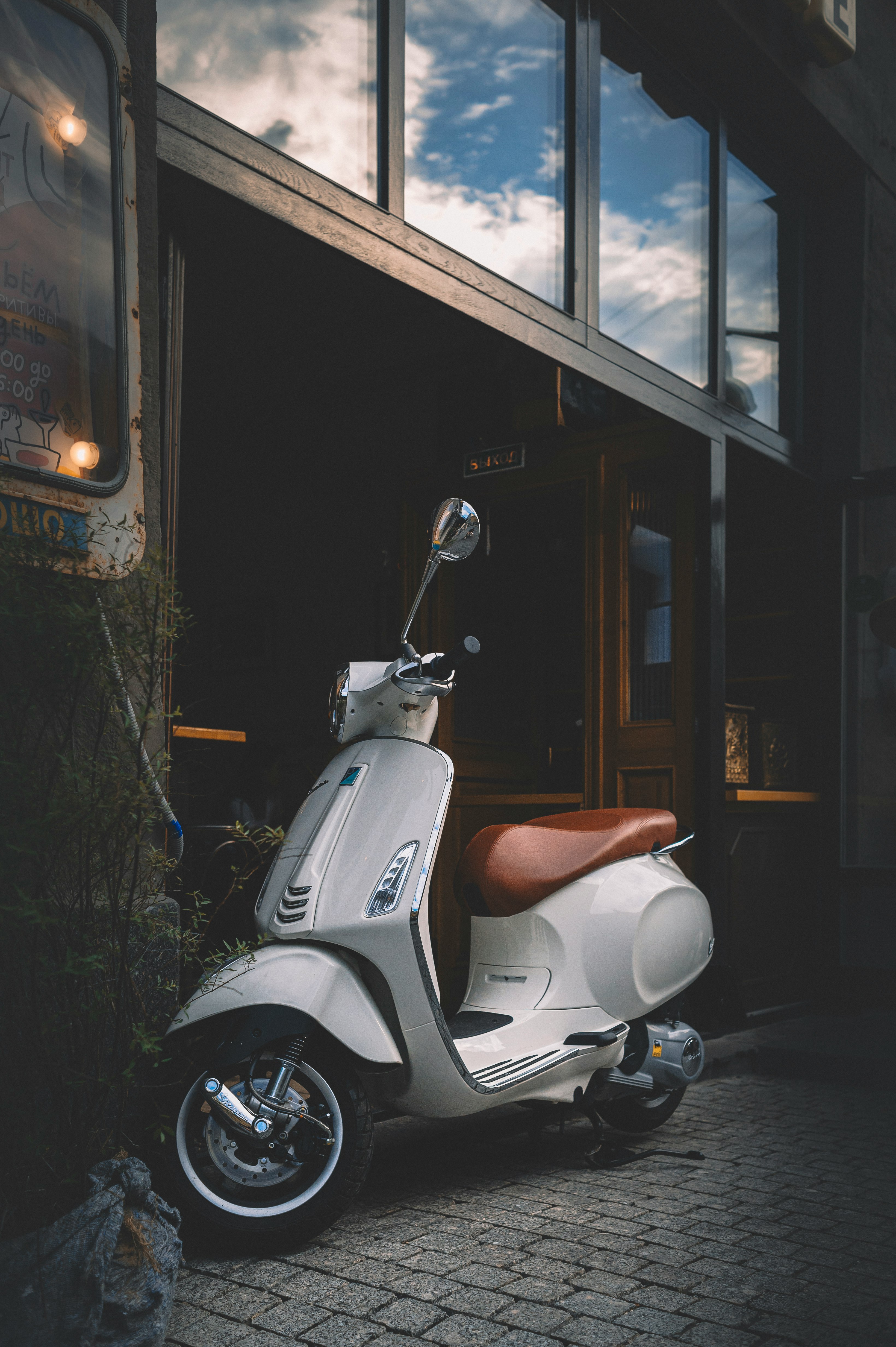 white motor scooter parked beside building during night time